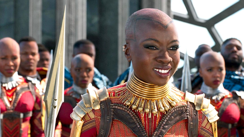 Danai Gurira en tant qu'Okoye souriant avec les Dora Milaje derrière elle dans Black Panther.