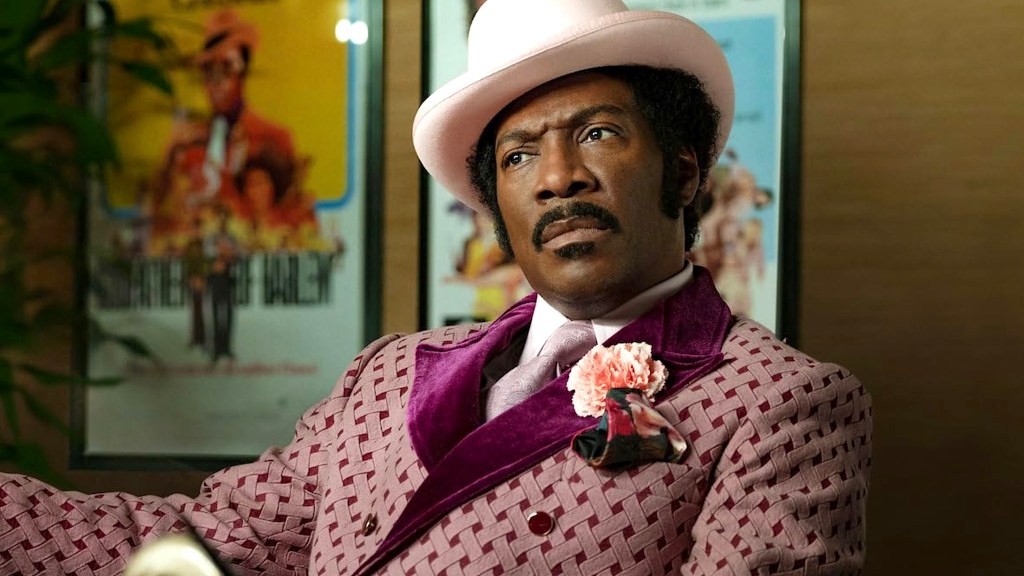 Eddie Murphy portant un costume rose avec une fleur rose et un chapeau dans Dolemite Is My Name