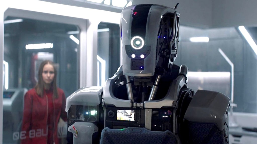 Un robot argenté avec une fille en rouge en arrière-plan