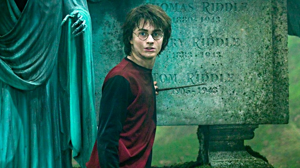 Daniel Radcliffe dans le rôle de Harry Potter tenant une baguette magique devant une statue en pierre.